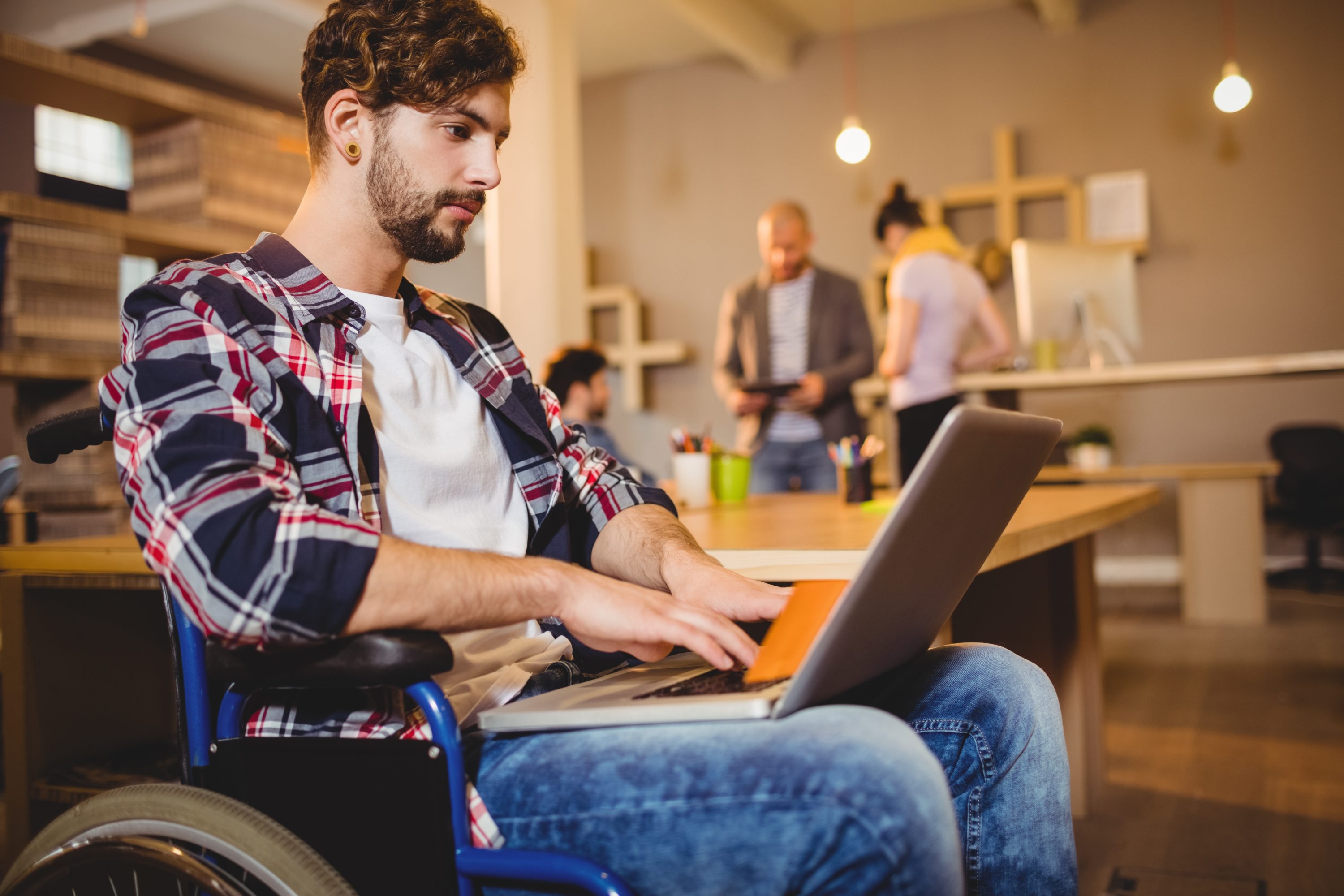 Man in wheelchair on laptop at office