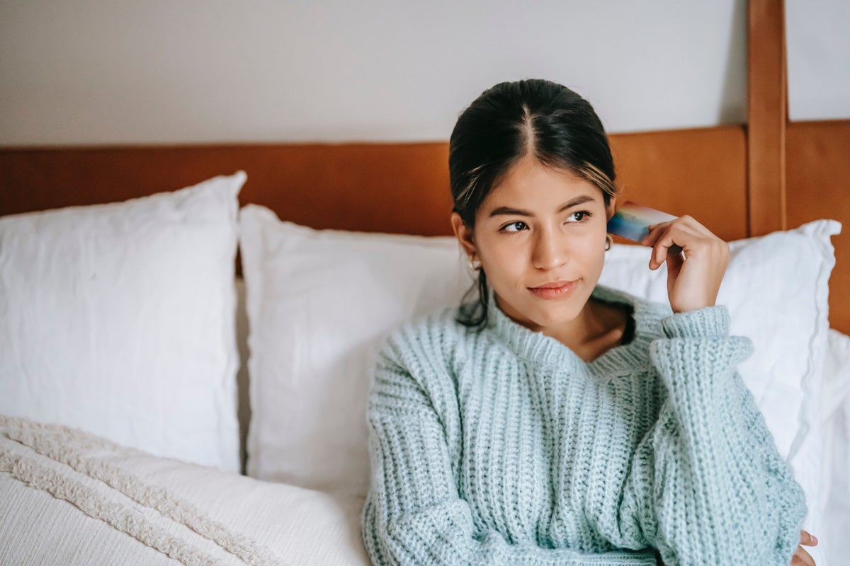 Woman in bed thinking about credit card