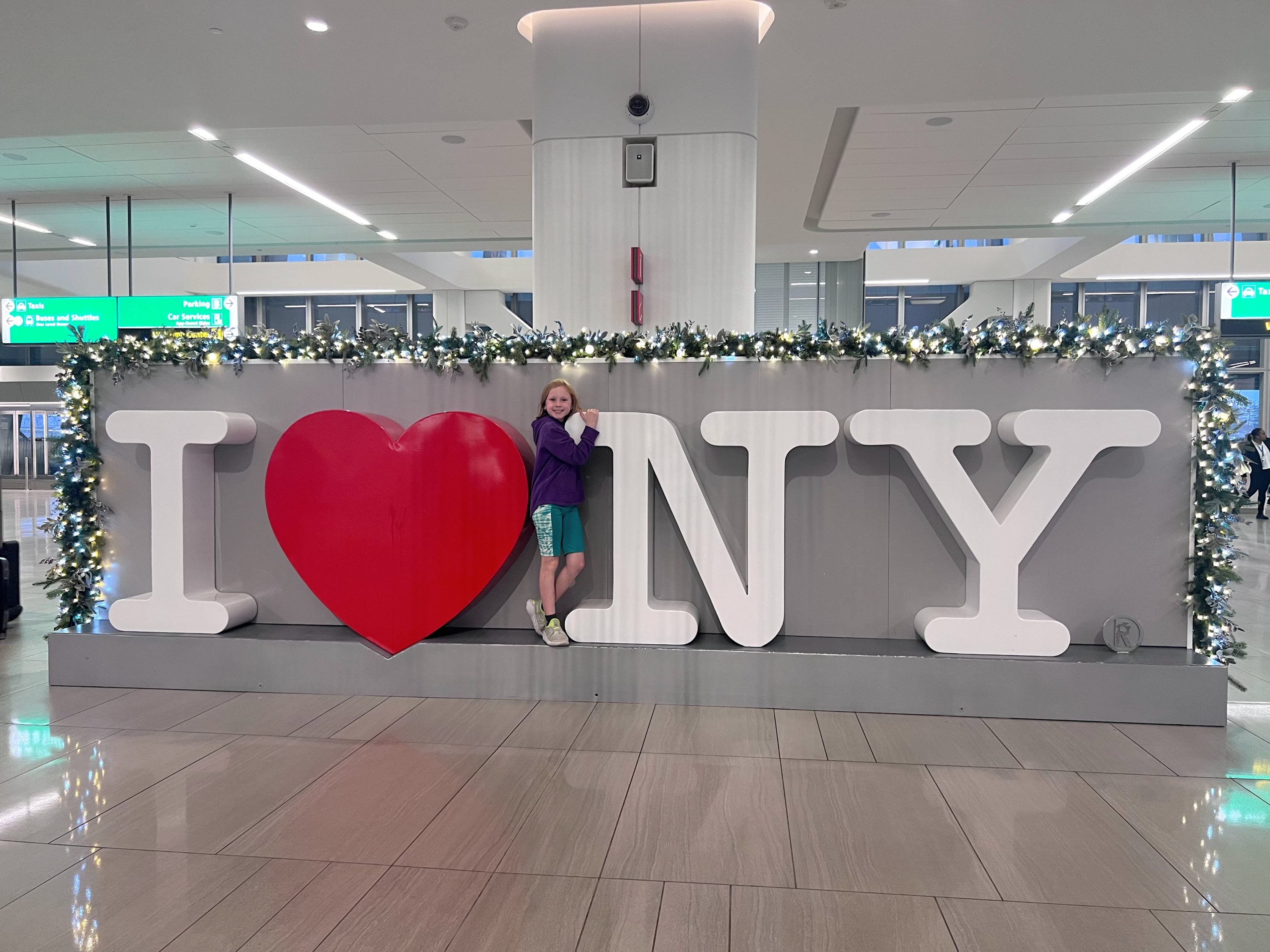 child standing by the I Love NY sign at LaGuardia airport