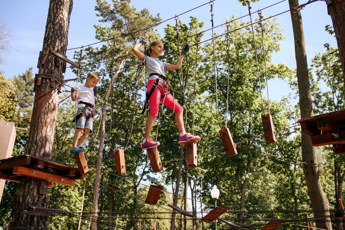Two kids do a ropes course at a summer camp.