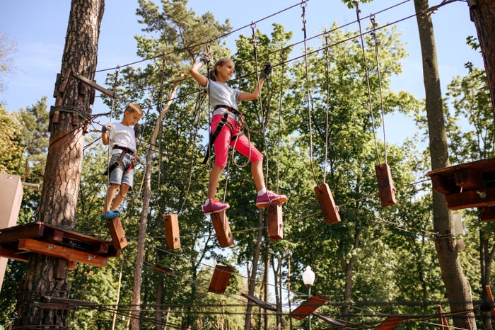 Two kids do a ropes course at a summer camp. Two kids do a ropes course at a summer camp.