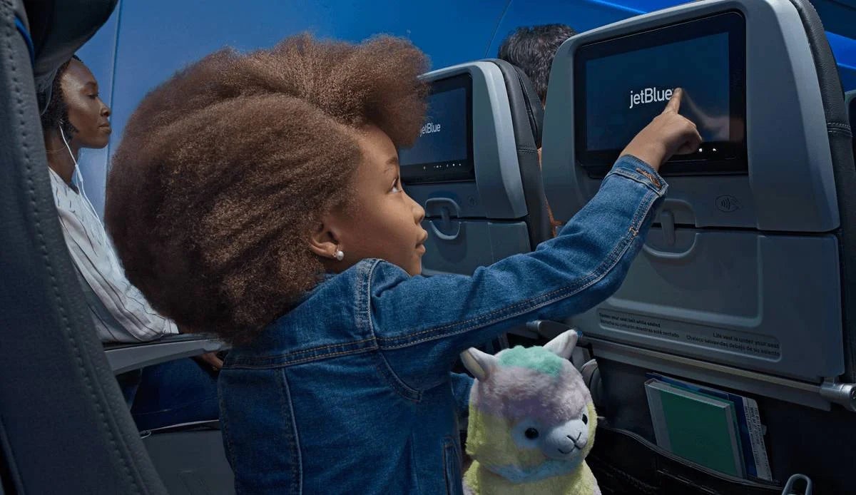 Child touching in-flight entertainment screen on a JetBlue flight copy