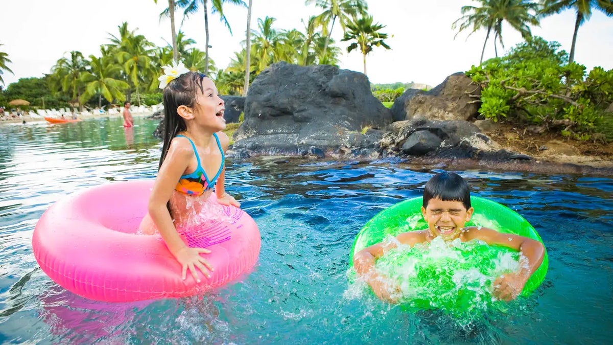 Two kids playing in the pool with toys at the Grand Hyatt Kauai Resort & Spa.