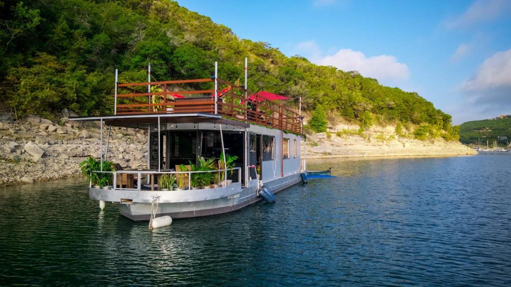 A houseboat on the water with live plants and a rooftop.