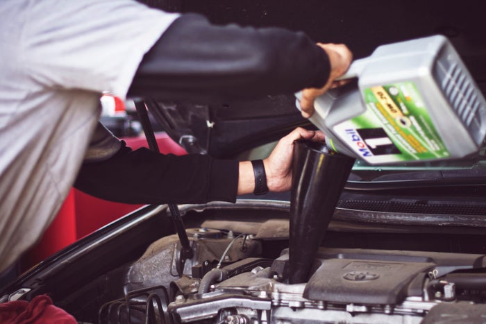 Person pouring oil into engine Person pouring oil into engine