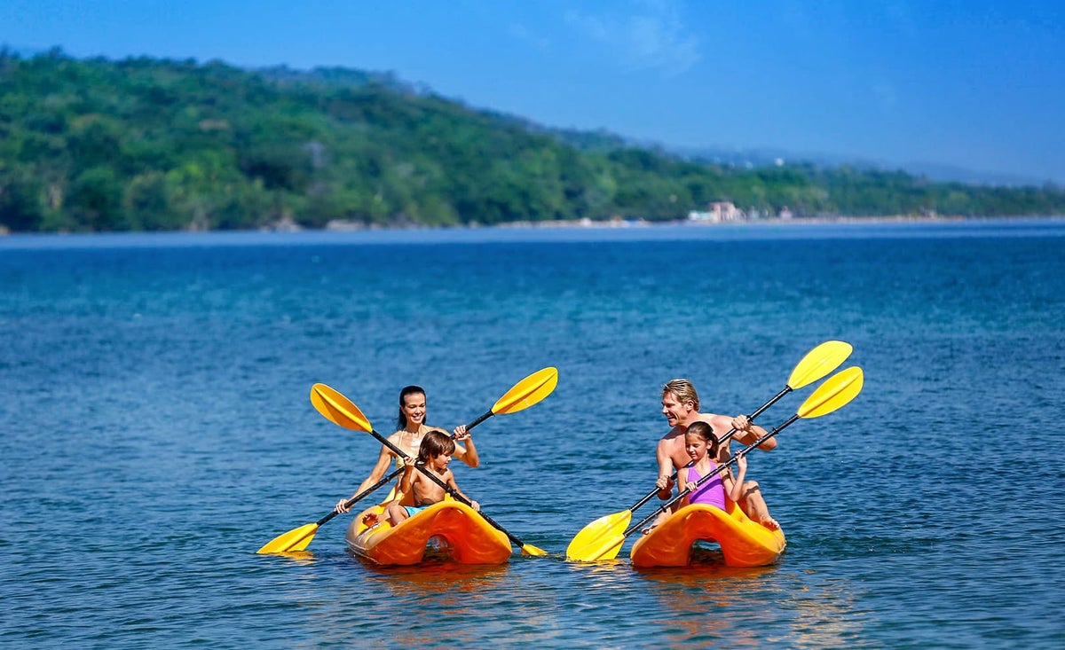 A family kayaks in the ocean at Moon Palace Jamaica.