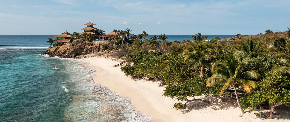 A photo of Necker Island with beach and lush landscape in the foreground.