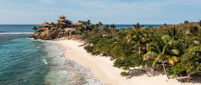 A photo of Necker Island with beach and lush landscape in the foreground. A photo of Necker Island with beach and lush landscape in the foreground.