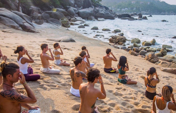 Vikasa Samui A group of people doing yoga on a beautiful beach