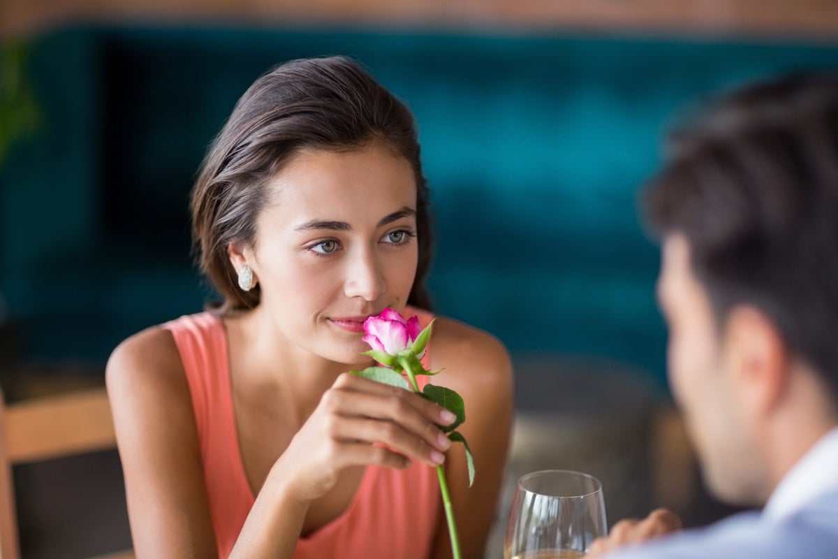 Woman smelling a rose offered by man