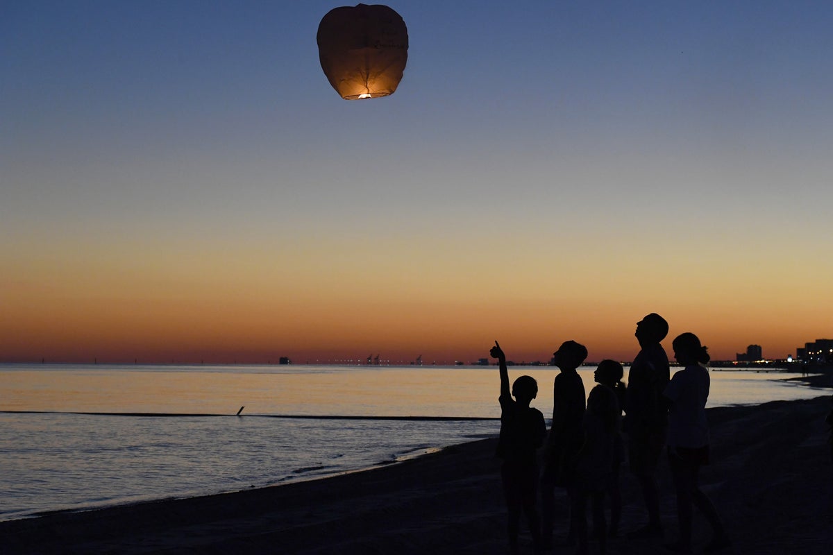 Family Launching Paper Lantern Over Water