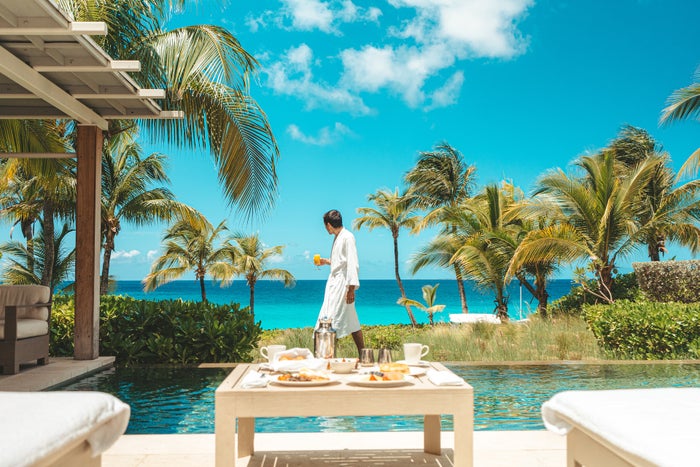 Poolside breakfast Anguilla A man walks by a pool holding orange juice