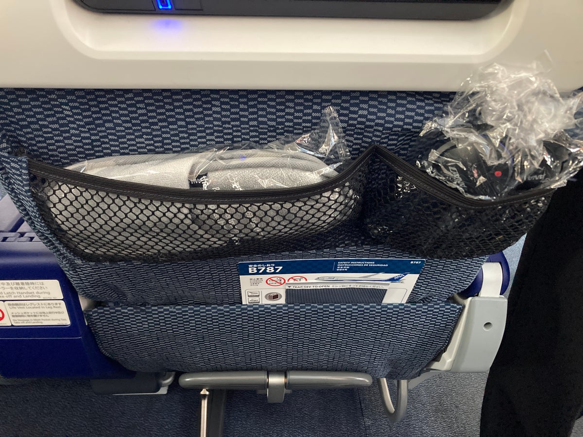 ANA premium economy Boeing 787 seat pockets with headphones and slippers