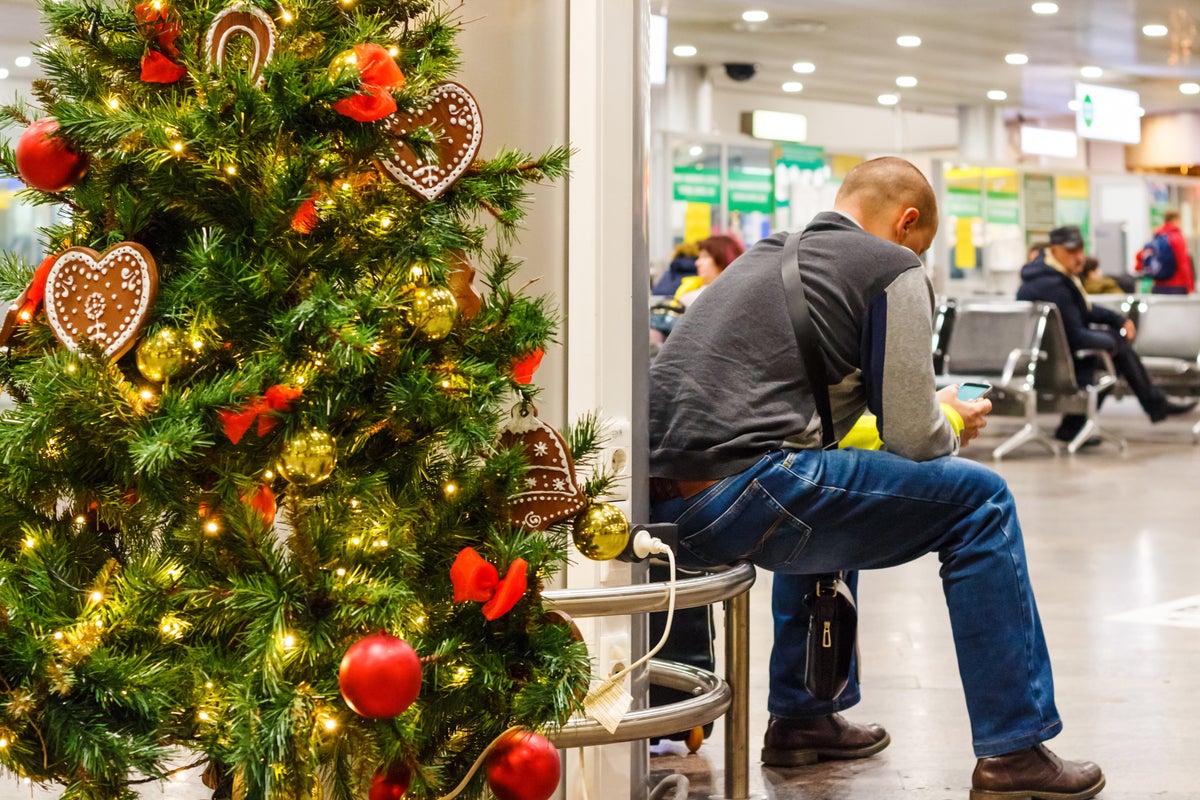 Man waiting for flight at airport next to Christmas tree