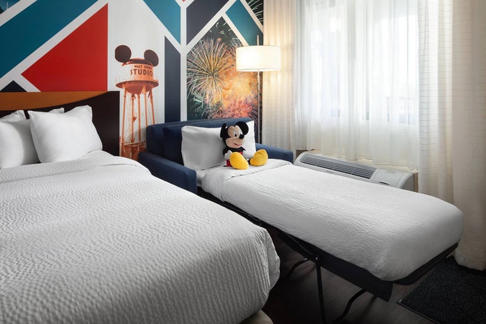 Guestroom at Fairfiled Anaheim A photo of a guestroom at Fairfiled Anaheim Resort shows a pullout sofa bed with a Mickey Mouse stuffed animal against a pillow.
