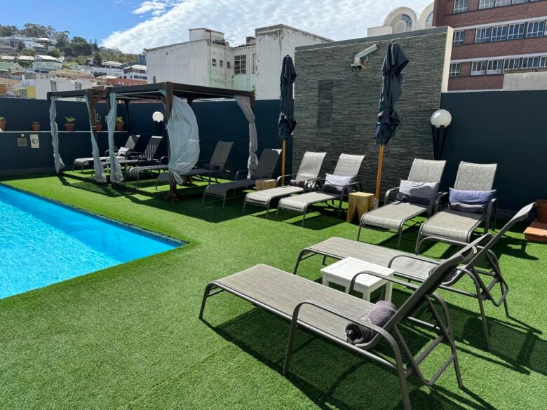 Hyatt Regency Cape Town pool area with dark grey cabanas with white sheets and grey lounge chairs.