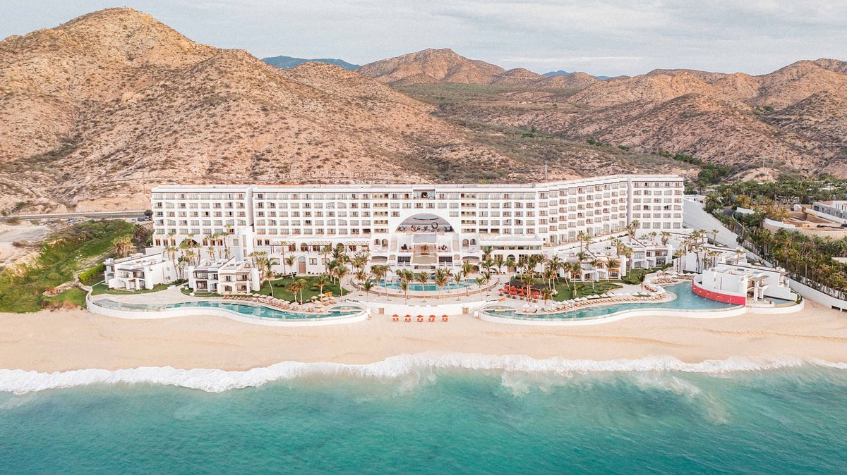A photo of Marquis Los Cabos from the ocean featuring 3 pools and hills in the background.