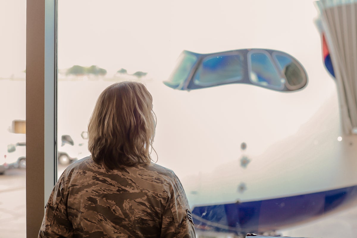 Military woman in airport looks at British Airways plane