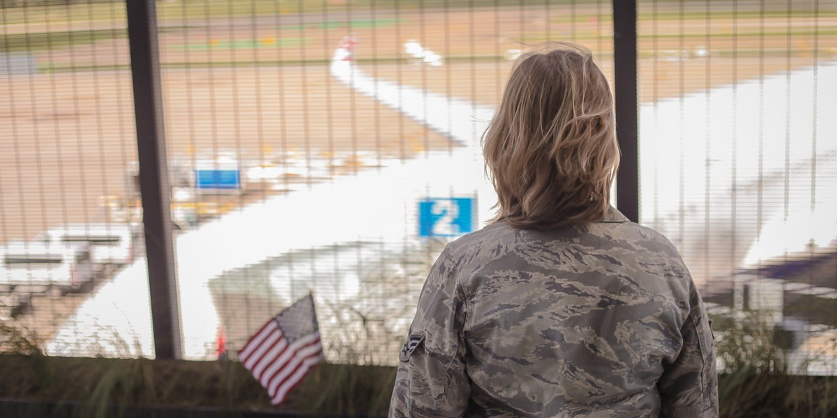 Military woman in airport overlooking plane