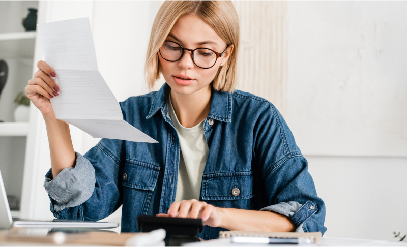 Woman reviewing paperwork with calculator