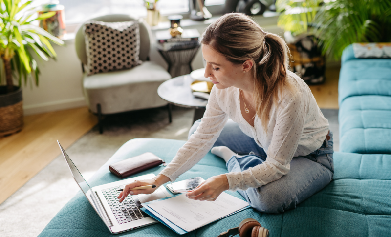 Woman reviewing paperwork with laptop