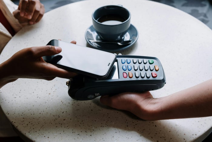 Person Tapping An iPhone Against A Payment Terminal