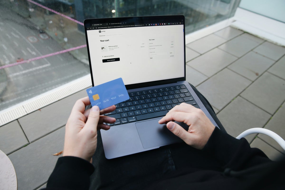 Person using computer holding credit card