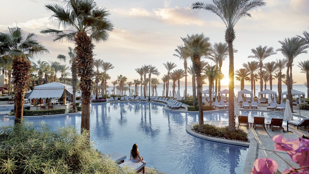 Pool, palm trees, and sunset over the sea