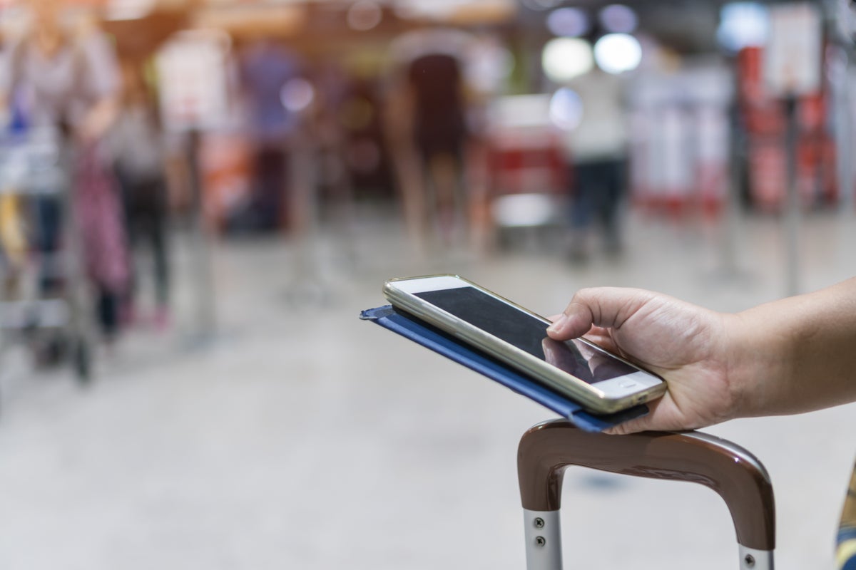 Hand holding phone at airport